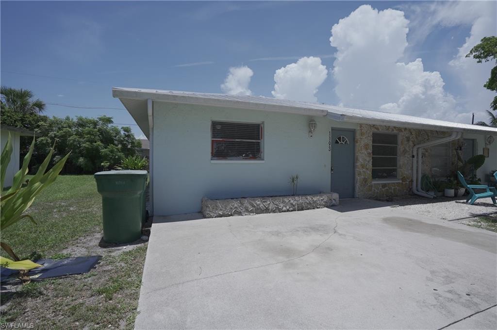 The property features a light blue exterior with stone accents, a concrete driveway, and a white roof
