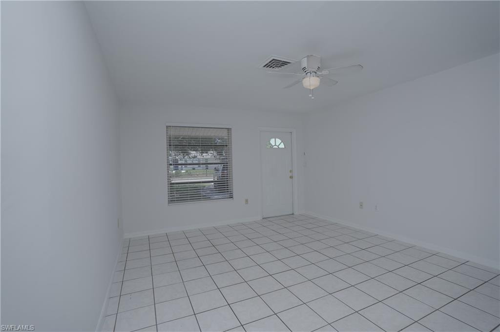 This bright room features tiled flooring, white walls, and a ceiling fan with integrated lighting