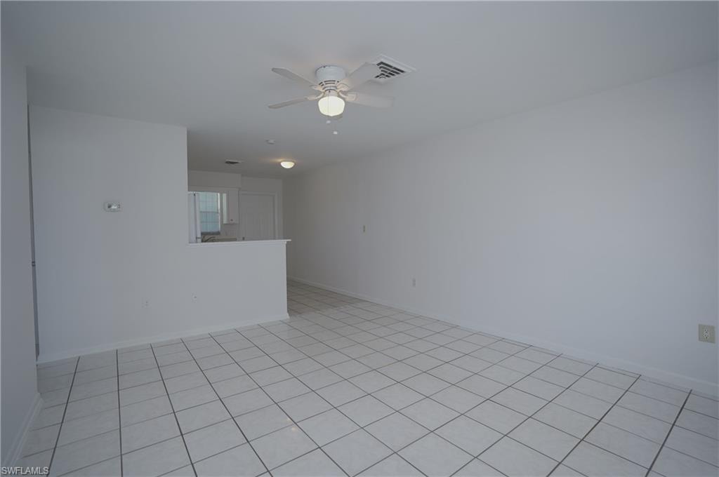 Living area featuring white tile flooring, light-colored walls, and a ceiling fan