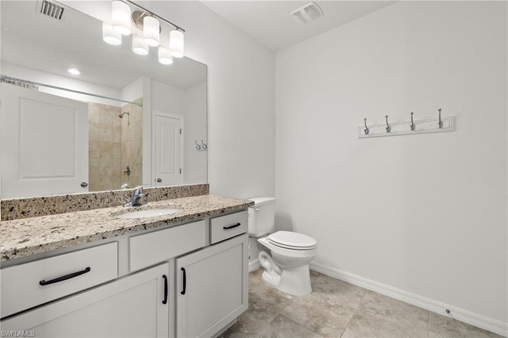 Bathroom with tile flooring, large vanity, and toilet