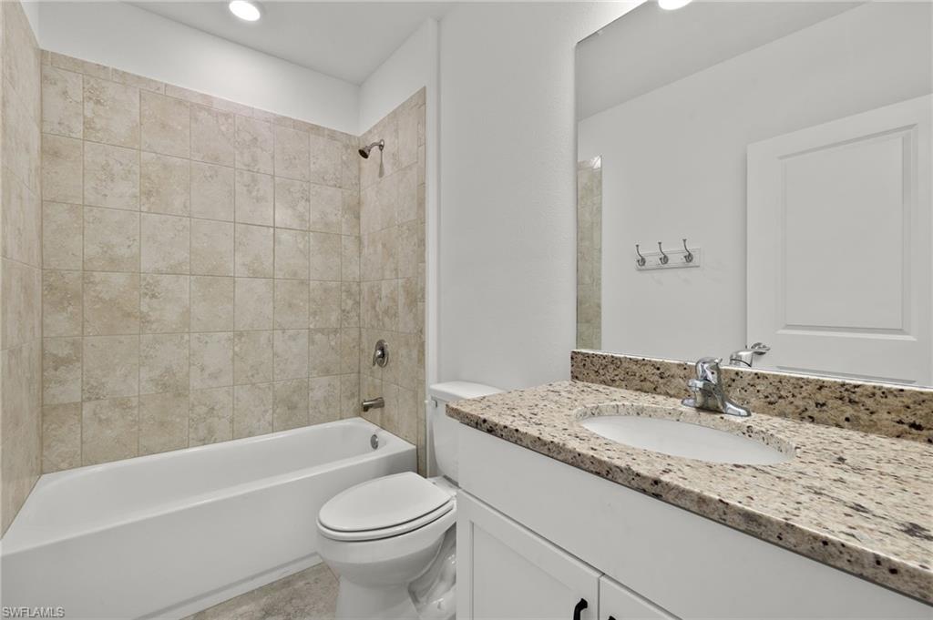 Full bathroom with toilet, tiled shower / bath combo, and oversized vanity