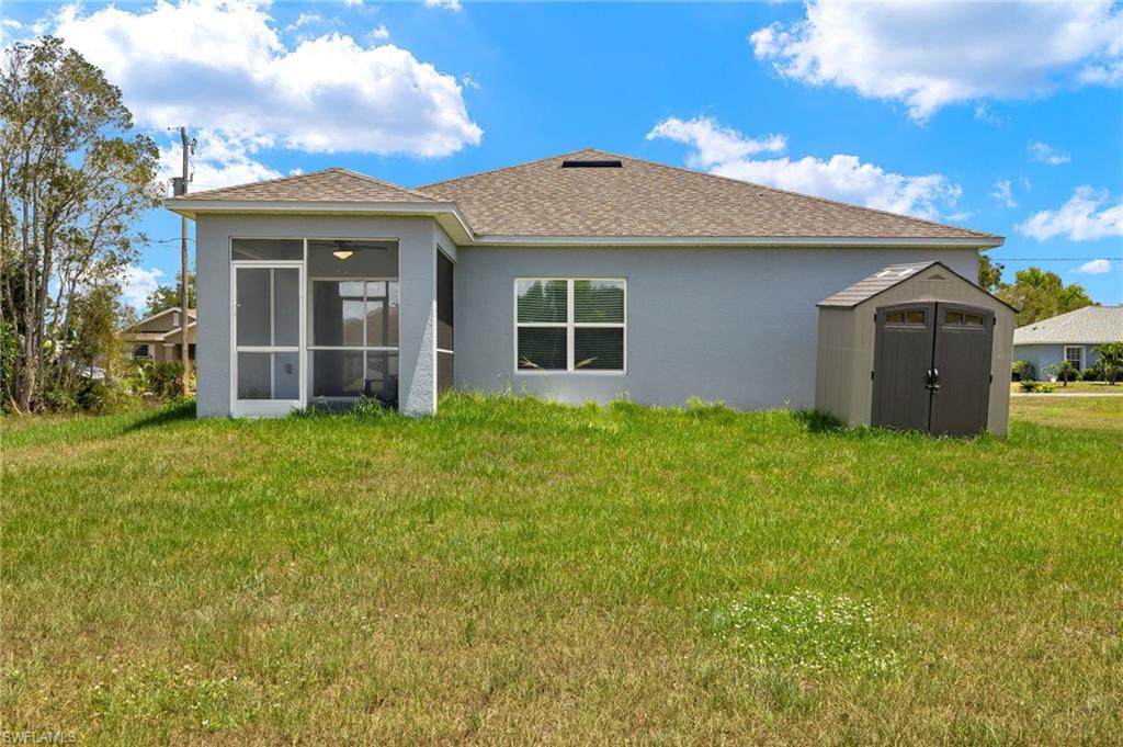 Back of property with a sunroom, a storage shed, and a yard