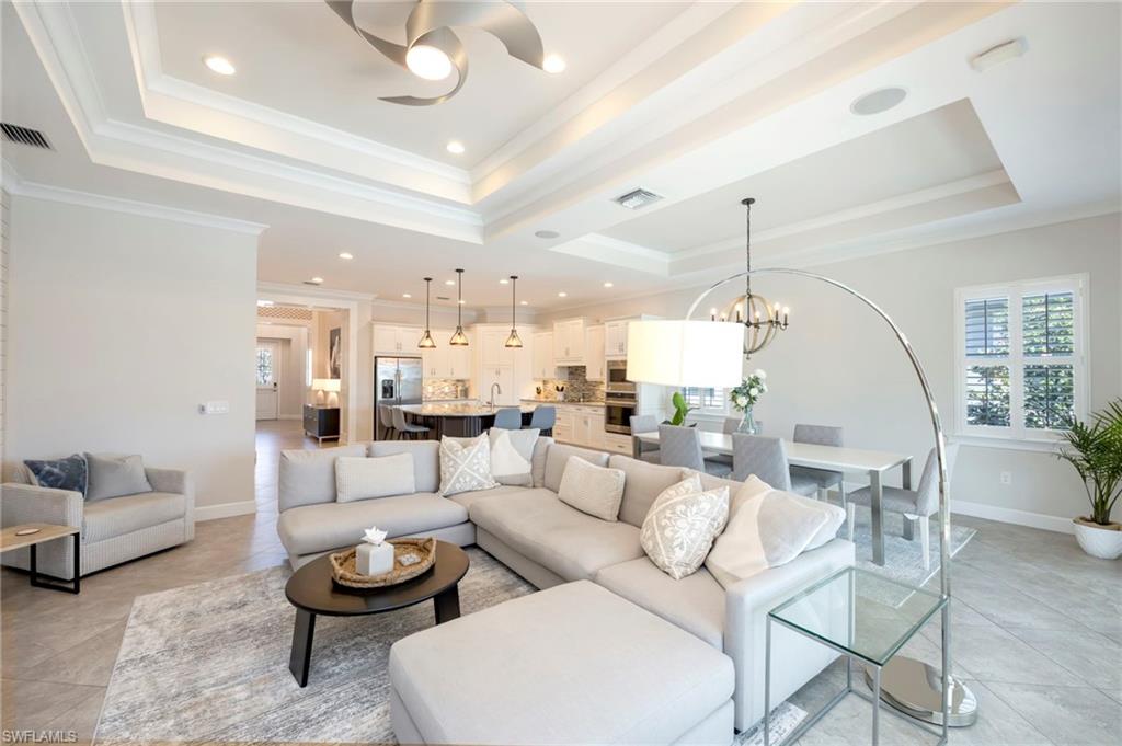 Living room has layered tray ceilings with crown moulding