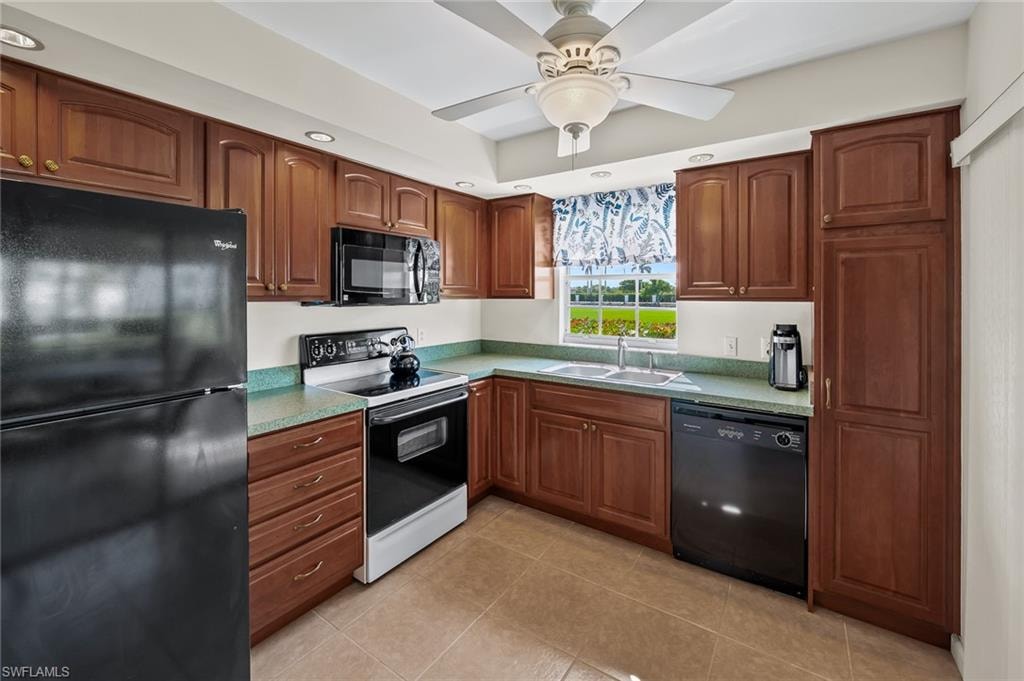 Kitchen featuring a sink, ceiling fan, brown cabinets, black appliances, and light tile patterned flooring