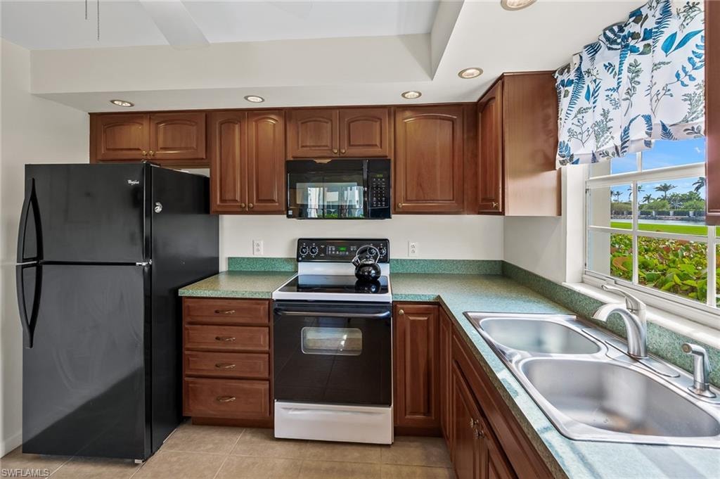 Kitchen featuring recessed lighting, light tile patterned floors, a sink, and black appliances