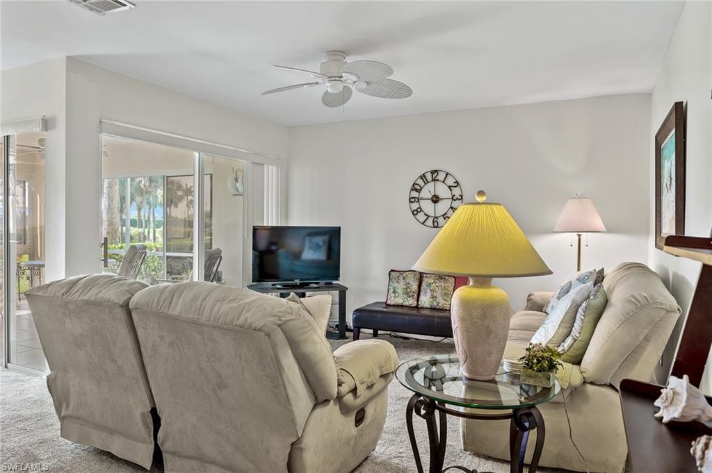 Living area featuring carpet flooring, visible vents, and ceiling fan