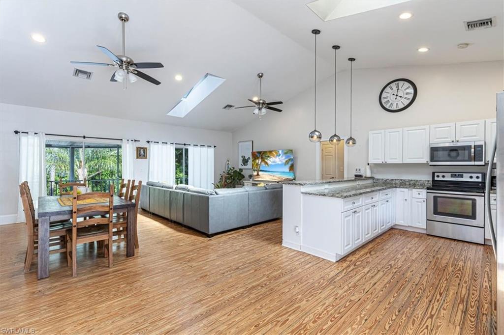 Kitchen featuring a ceiling fan, a skylight, appliances with stainless steel finishes, high vaulted ceiling, and pendant lighting