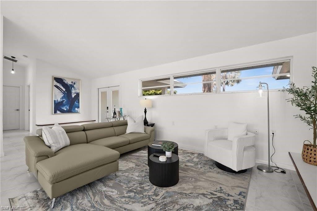 Living area featuring white walls, a large area rug, and a row of high windows