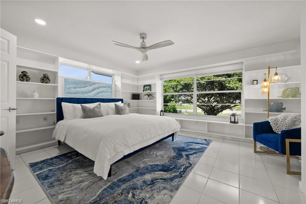This room features white tile flooring, large windows providing expansive views of trees and green space, and extensive built-in shelving