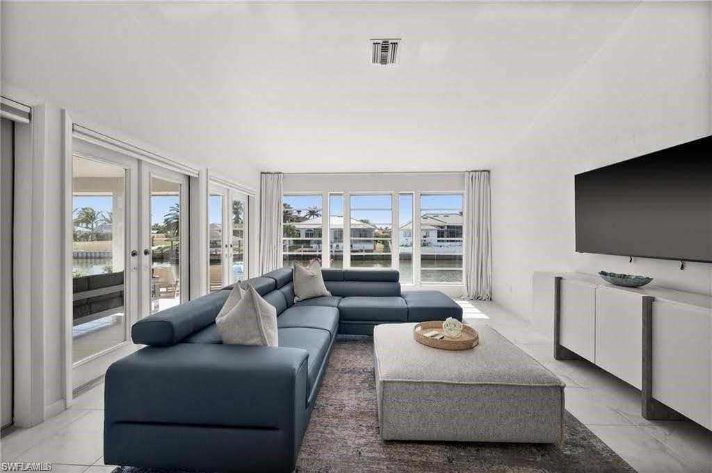 Primary bedroom sitting area featuring large windows and glass doors providing abundant natural light and views of the waterway