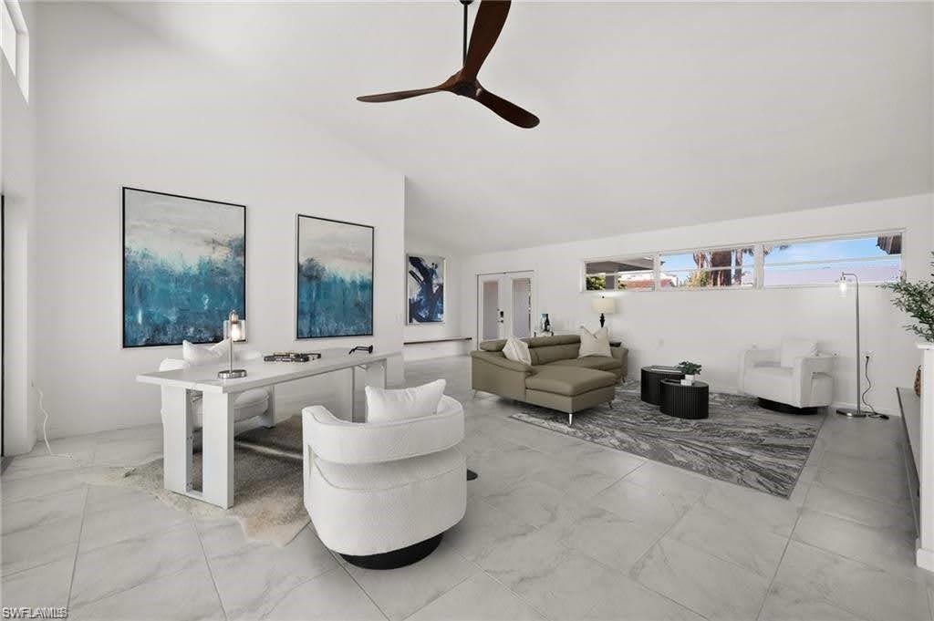 Expansive living area featuring vaulted ceilings, a ceiling fan, and large tile flooring