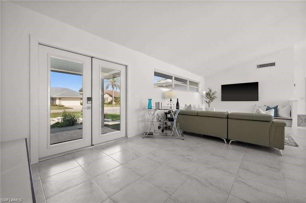 The dwelling features light-colored tile flooring throughout, white walls, and French doors that open to the exterior