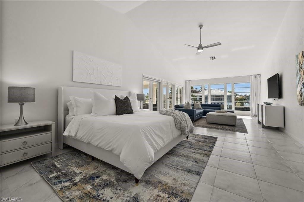 The primary room features tall ceilings, tile flooring, and large windows that provide views of the water