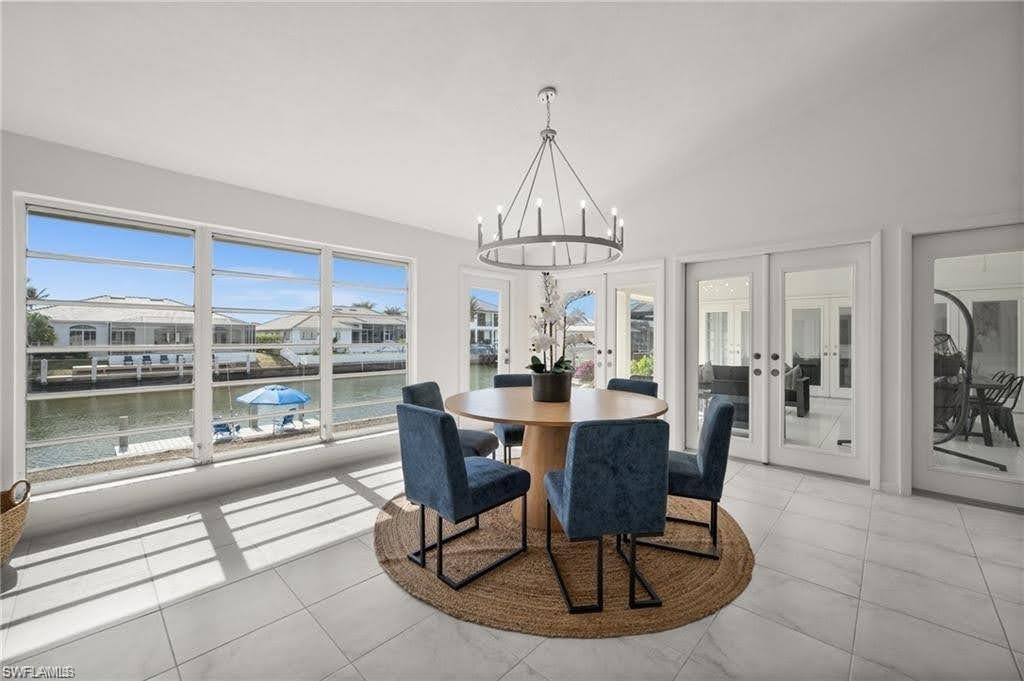 This bright dining space features a vaulted ceiling, large windows overlooking a canal, and french doors leading to the oversized patio