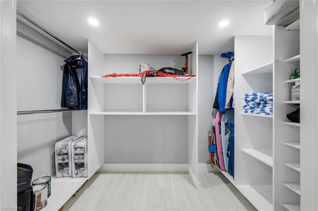 Walk-in closet featuring extensive built-in shelving and hanging rods, recessed lighting, and light-colored flooring