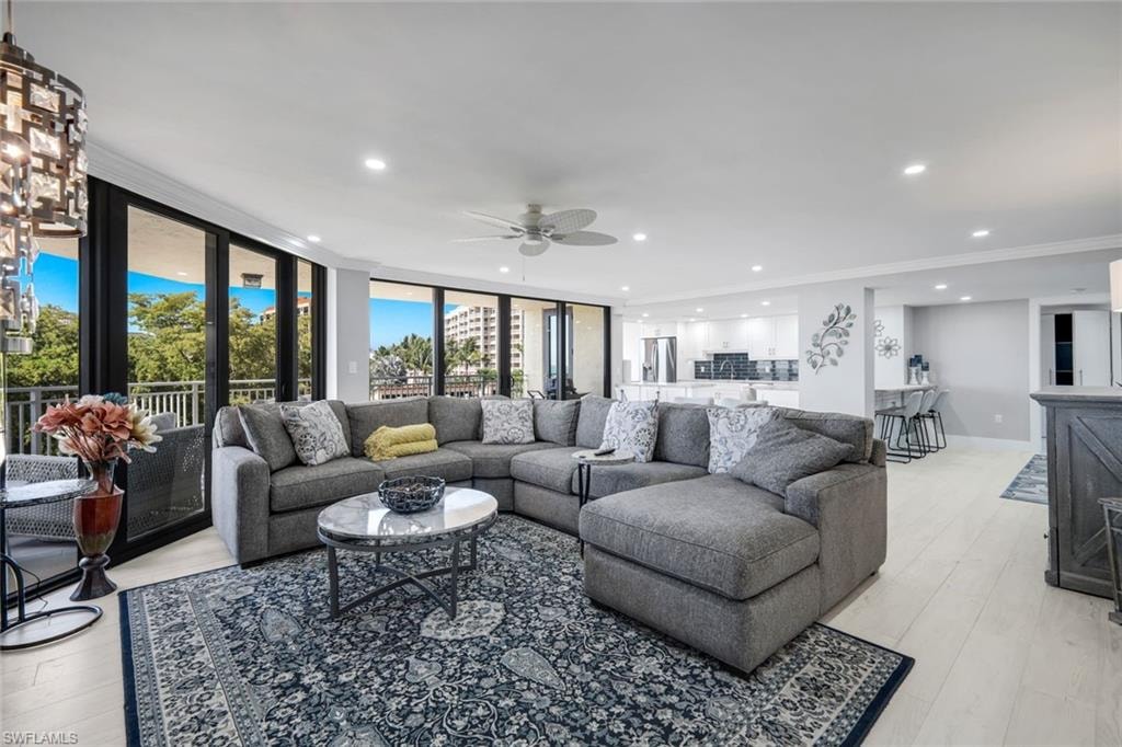 This expansive living area features light-colored flooring, recessed lighting, and a ceiling fan