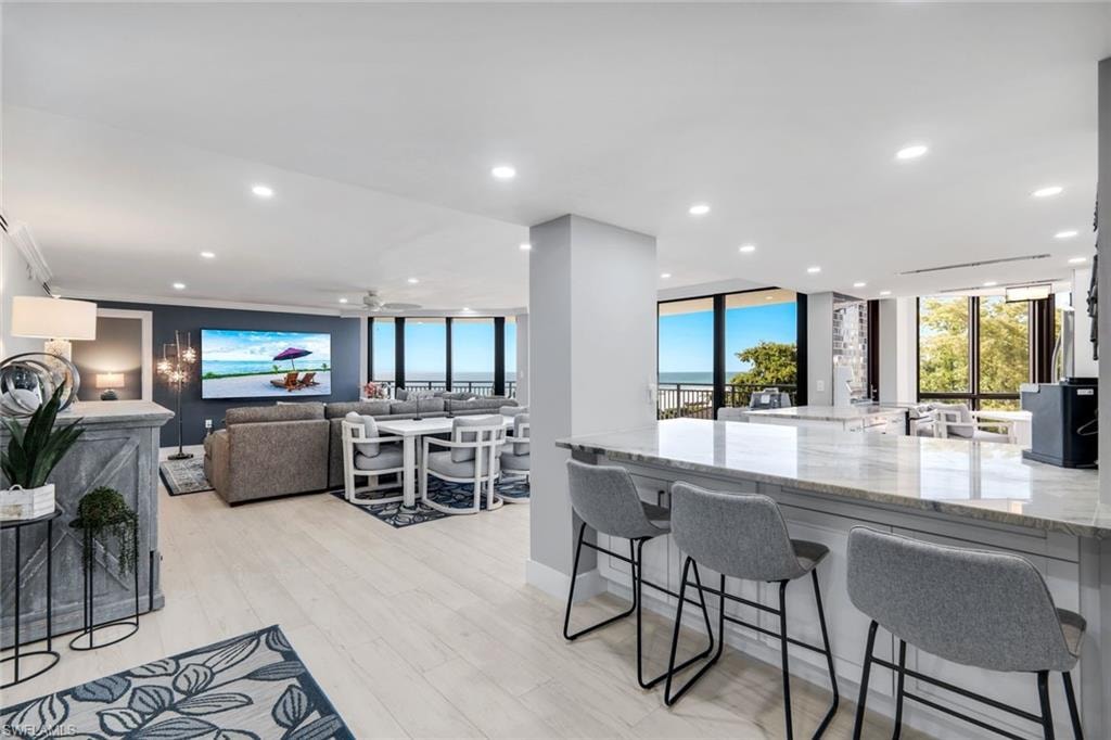 This open-concept living space features light-toned flooring, recessed lighting, and expansive windows offering views of the outdoors