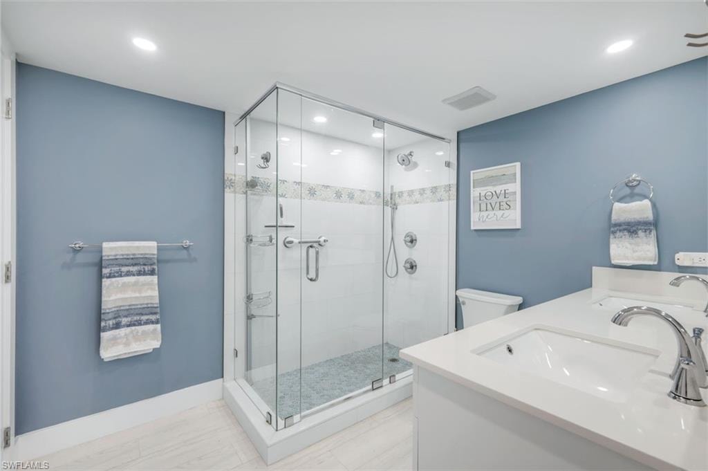 The bathroom features a spacious glass-enclosed shower with tile work, a dual vanity with undermount sinks, and contemporary fixtures