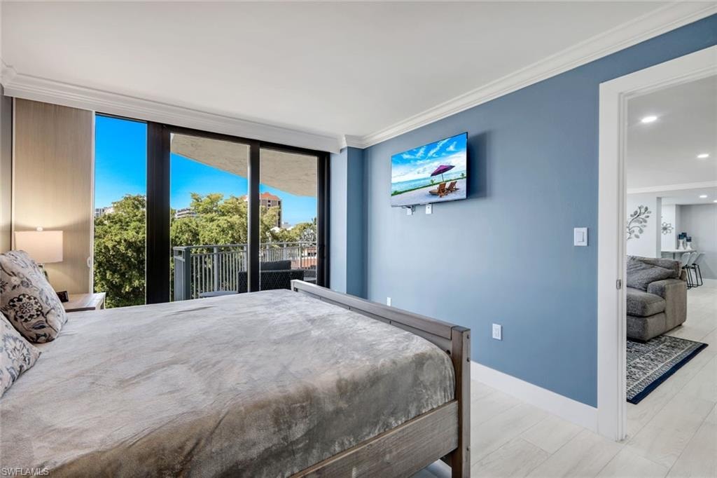 The room features light blue walls, white trim, and a sliding glass door that opens to a balcony with a metal railing