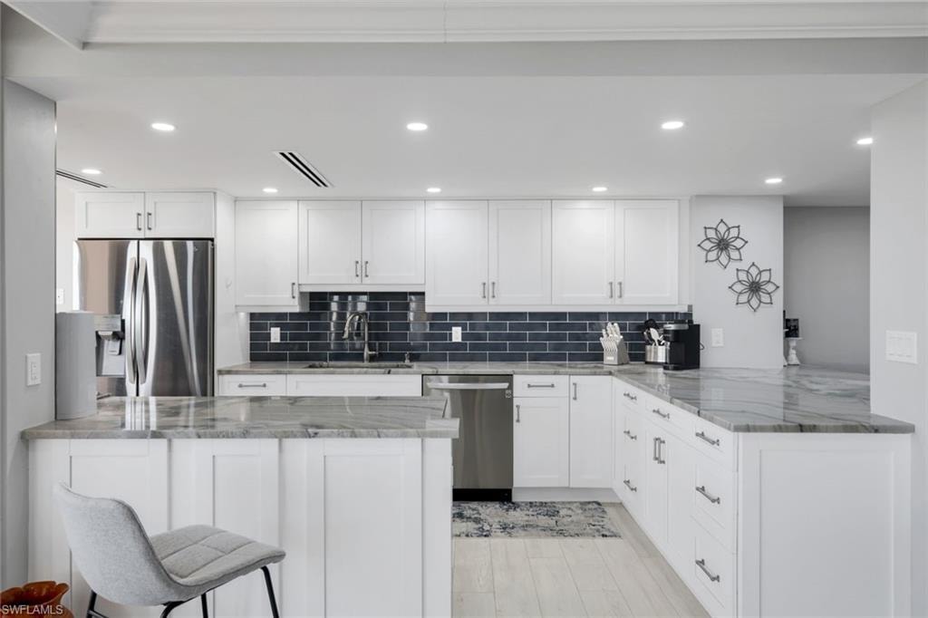 The kitchen showcases white cabinetry, a dark subway tile backsplash, and light-colored countertops
