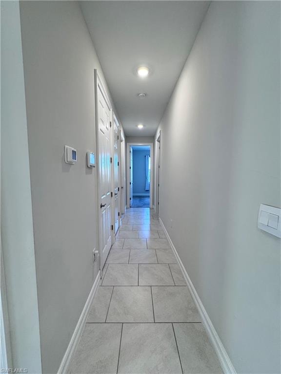 Corridor with light tile patterned floors and baseboards