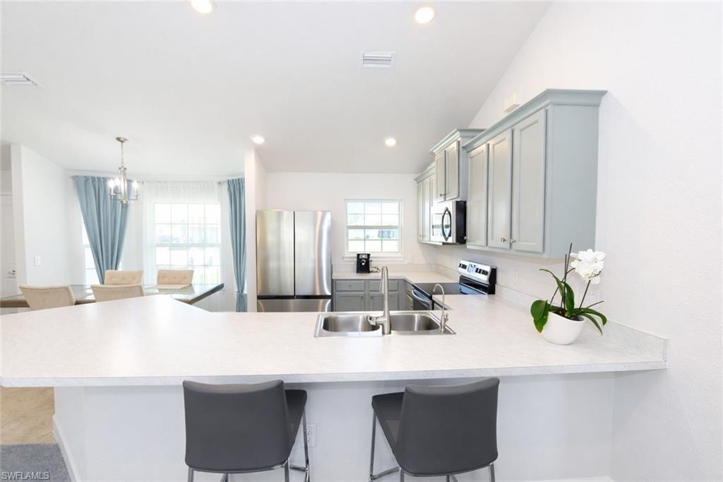 The kitchen features light-toned countertops, a double basin sink, and stainless steel appliances