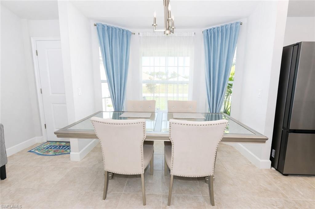 The dining area features light-colored tile flooring, a window with light blue drapery, and a modern light fixture