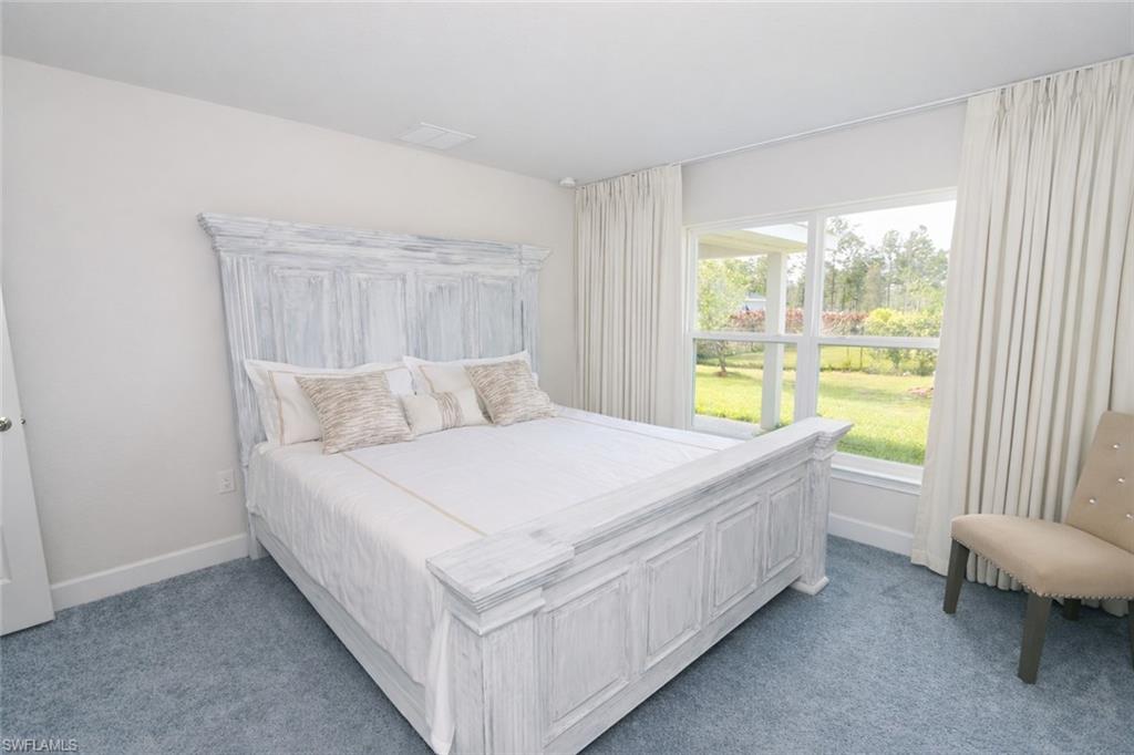 The property features light blue carpeting, white walls, and a large window providing views of the outdoor landscape