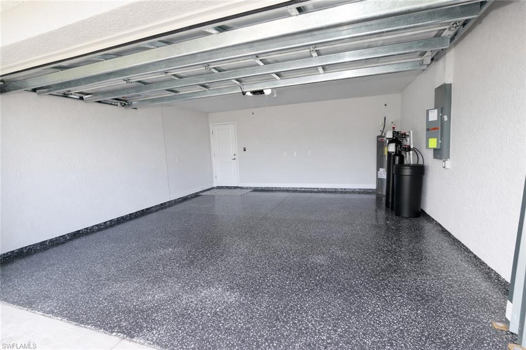 The garage features a speckled epoxy floor, white textured walls, and an overhead garage door mechanism