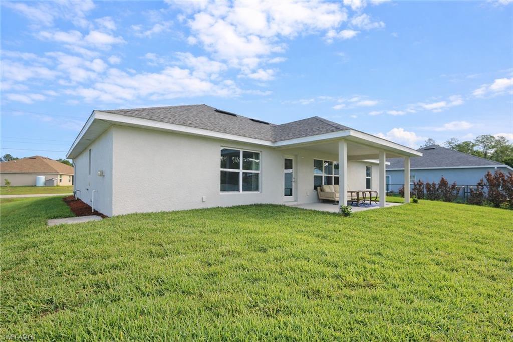 The property features a stucco exterior, a covered patio, and a spacious green lawn