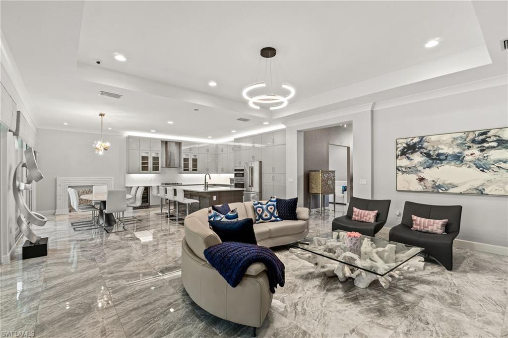 Elegant, open-concept living and dining space with designer lighting, custom finishes, including the custom fireplace facade in the dining area.