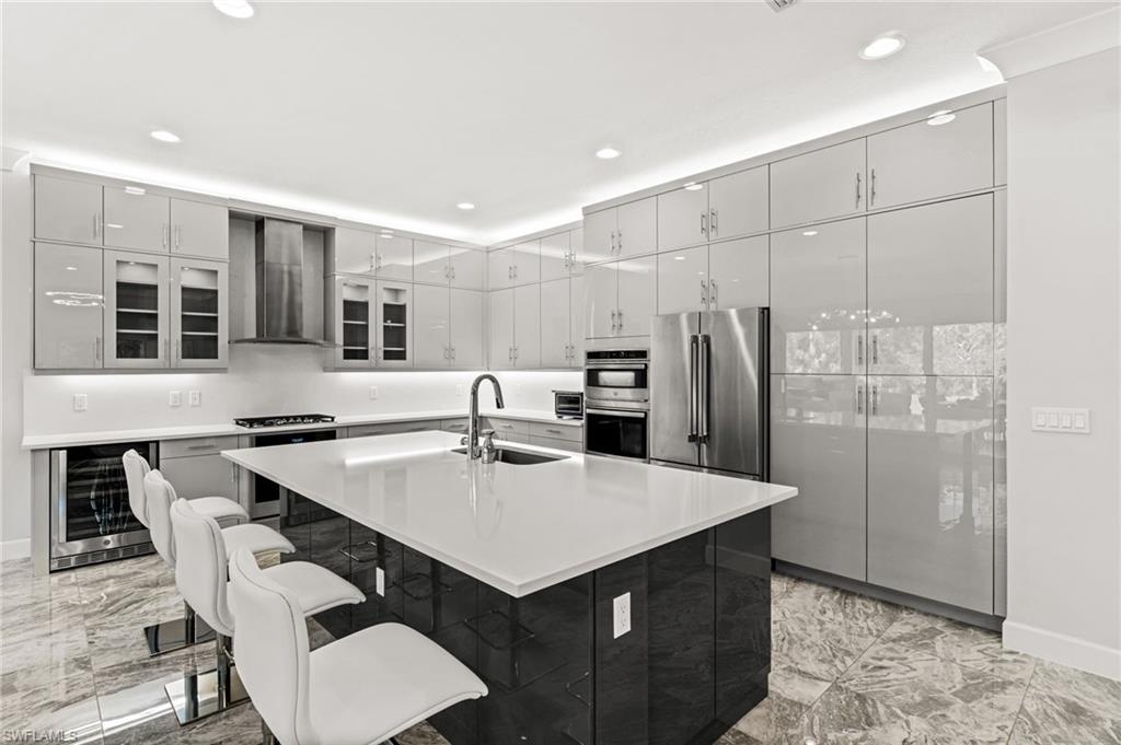 Sleek Euro cabinetry, extended upper cabinets, natural gas cooktop with stainless steel vent hood, a Thermador refrigerator, dual ovens, quartz counters and backsplash, plus wine fridge.