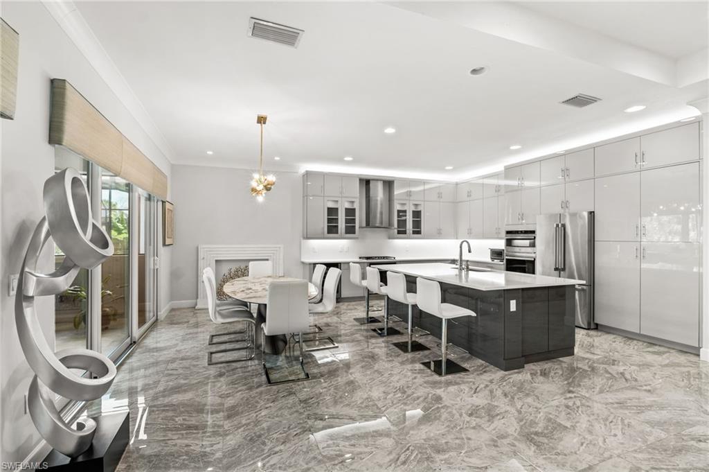 sleek Euro cabinetry, extended upper cabinets, gas cooktop with stainless steel vent hood, a Thermador refrigerator, dual ovens, quartz counters and backsplash, plus wine fridge.