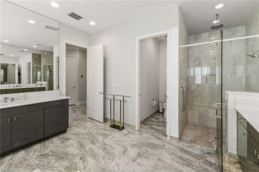 Primary suite bathroom with dual vanities, large walk in shower, water closet.