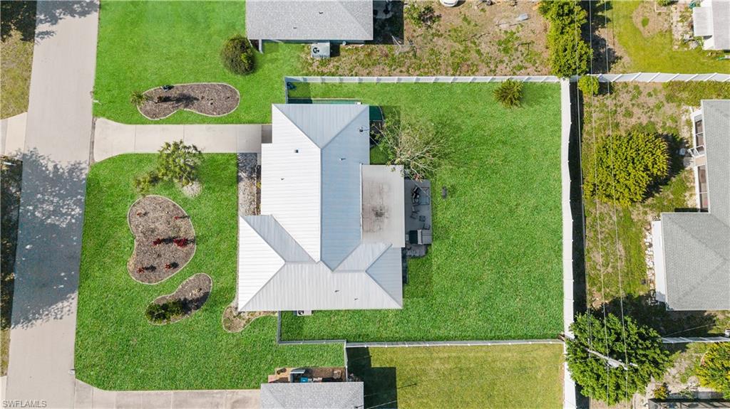 An aerial view showcases the property's expansive, well-maintained lawn, complemented by a white-fenced perimeter