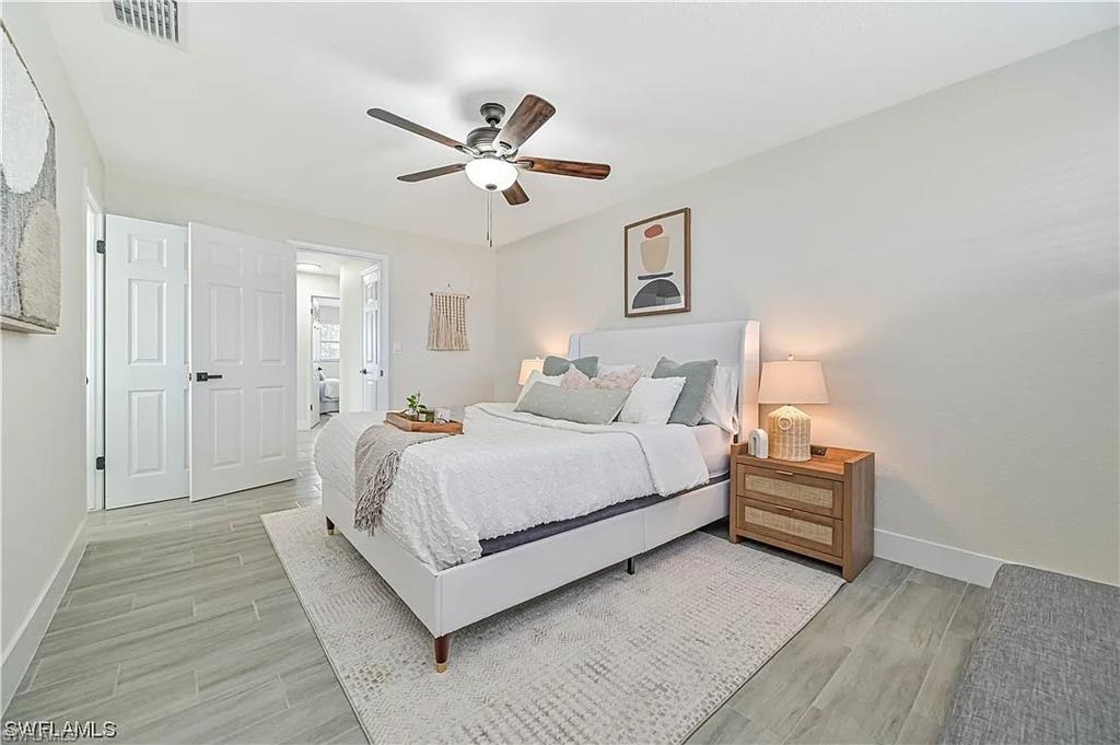 This room features light-toned flooring, a ceiling fan with light fixture, and white double doors