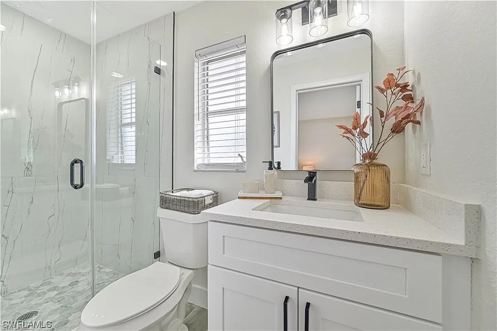 The bathroom features a modern vanity with a white countertop and a rectangular sink, complemented by a sleek black faucet and a framed mirror