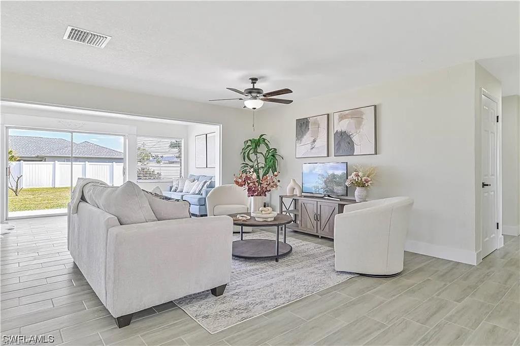 This spacious living area features light-toned tiled flooring, large windows, and a ceiling fan
