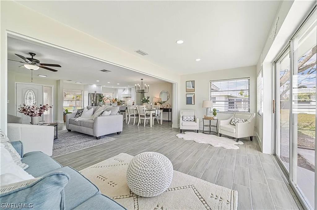 Expansive open-plan living area featuring light-toned flooring, recessed lighting, and large sliding glass doors providing outdoor access