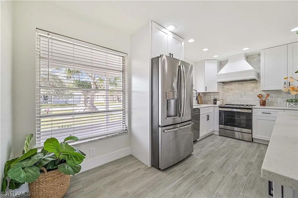 The kitchen features light-colored flooring, white cabinetry, a stainless steel refrigerator, and a stainless steel oven