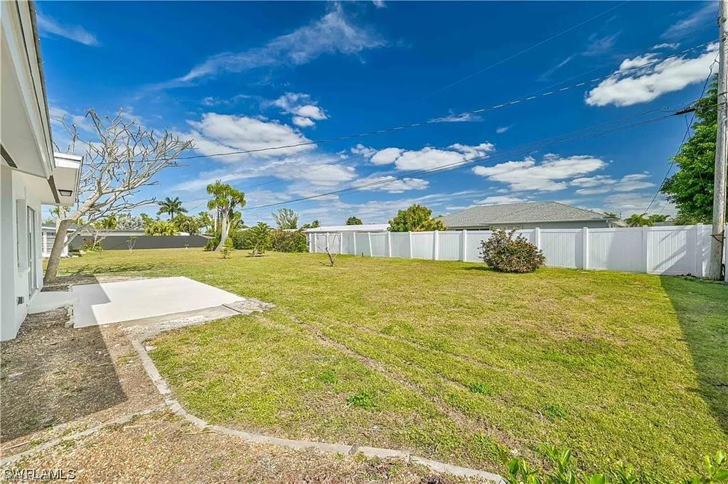 The property features an extensive green lawn with a white privacy fence