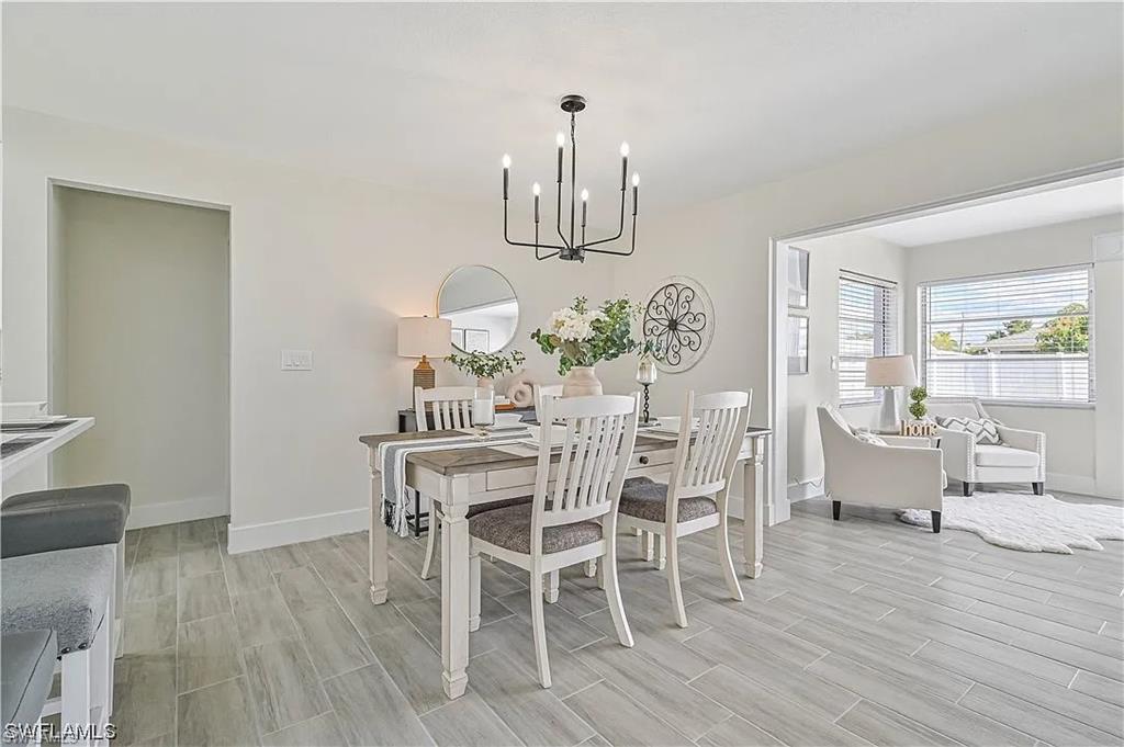 The dining area features light-toned flooring, a contemporary chandelier, and a wall mirror, creating a welcoming atmosphere