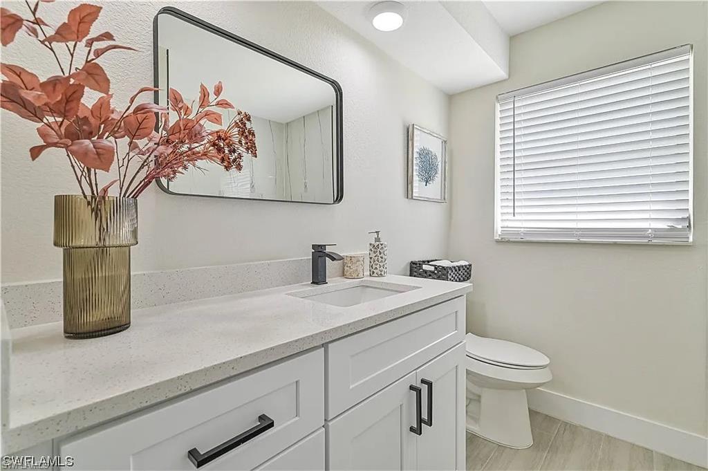 Well-appointed bathroom featuring a vanity with a white countertop, an integrated sink, and dark hardware on the cabinetry
