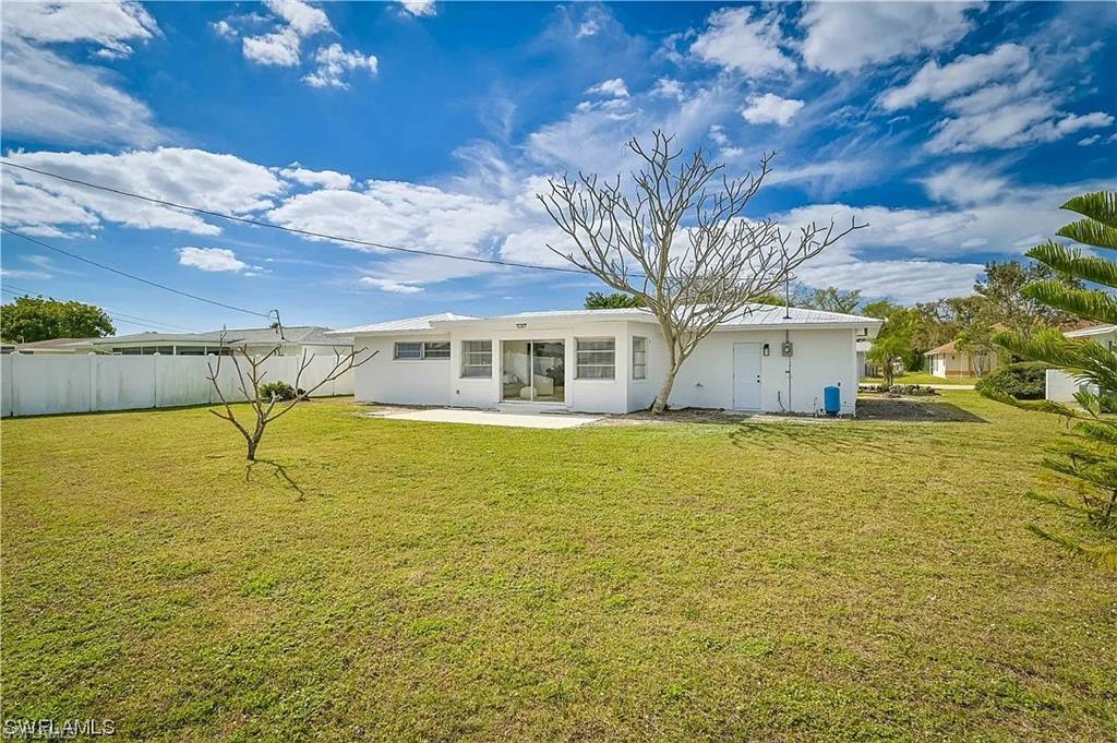 The property features an expansive lawn and a white exterior, complemented by mature trees