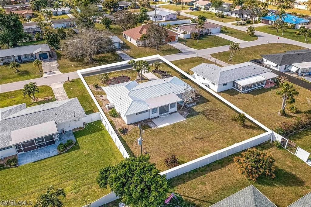 This property features a single-story residence with a light-colored roof, a screened-in lanai, and a spacious yard