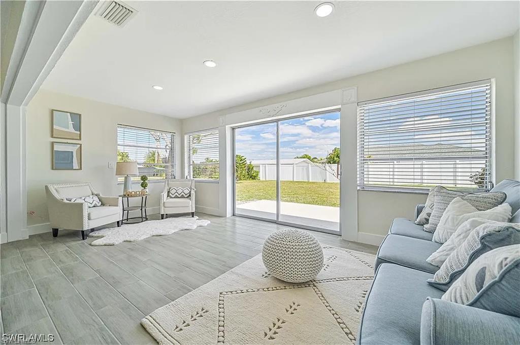 Spacious living area featuring light-colored flooring, recessed lighting, and large sliding glass doors leading to an outdoor patio and yard