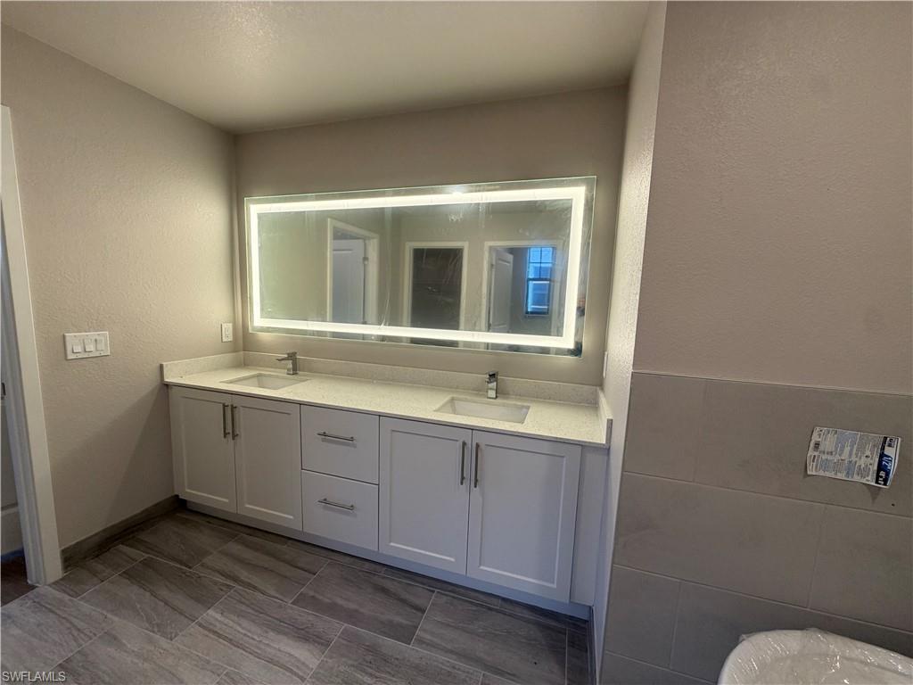 Bathroom featuring a double vanity with white cabinetry, light-colored countertops, and two undermount sinks