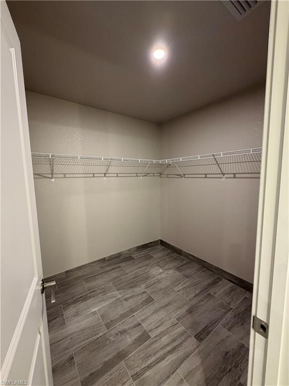 Spacious closet featuring tiled flooring, a ceiling light fixture, and wire shelving