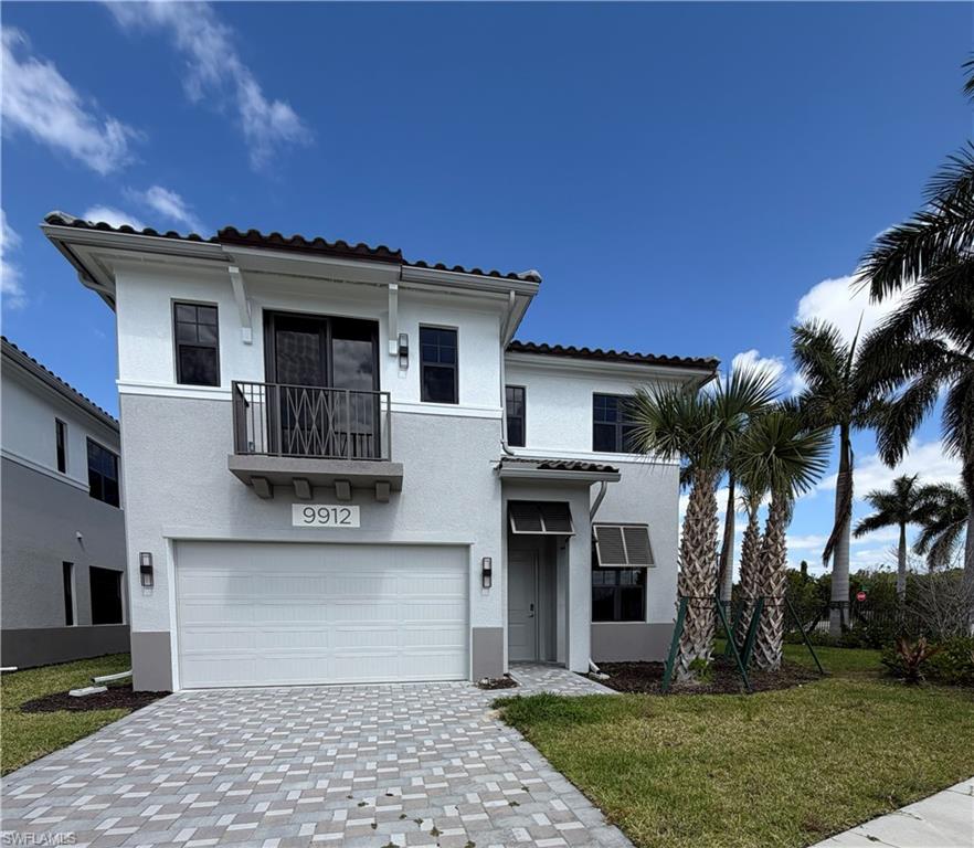 The property features a two-story stucco exterior with a tiled roof, an integrated garage, and a paver driveway