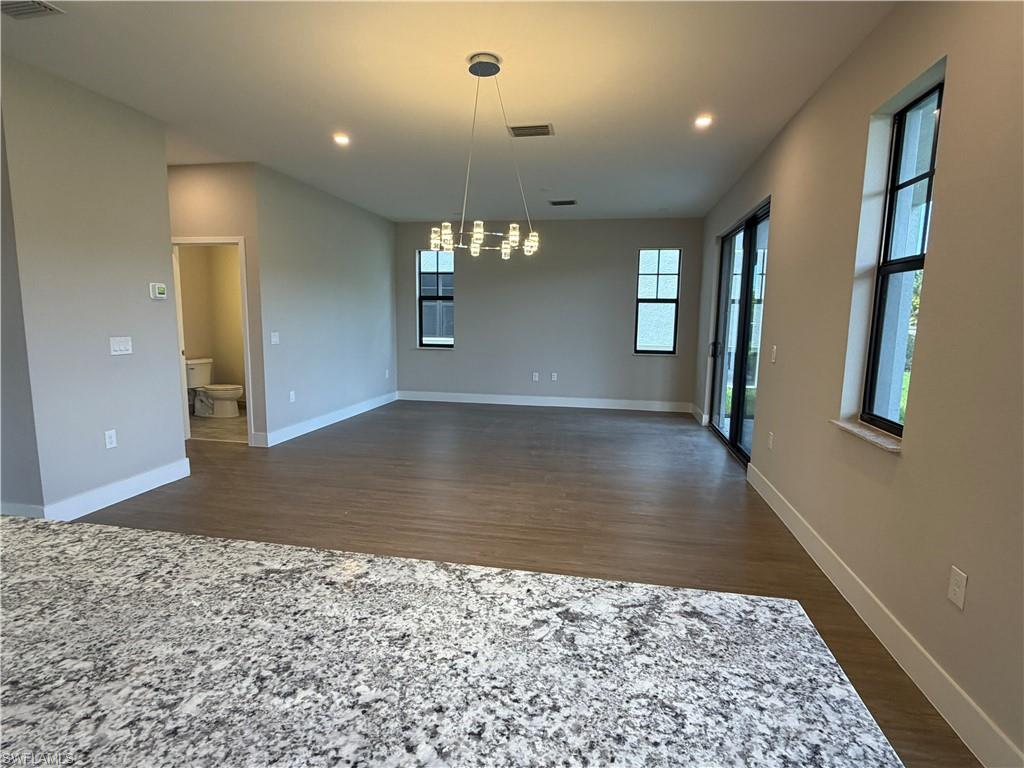 Spacious living area featuring light-colored walls, recessed lighting, and a modern chandelier